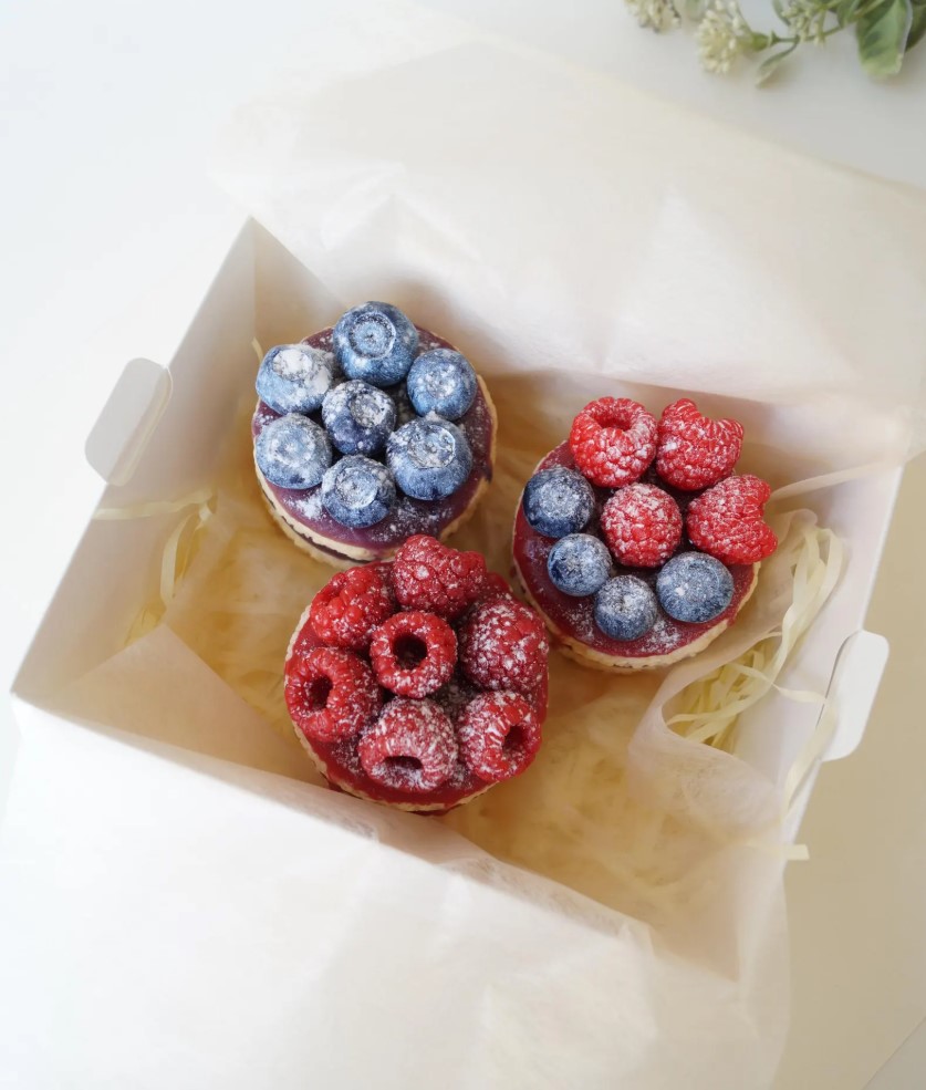 Three berry tart shaped soaps with raspberry and blueberry details in a white box